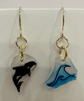 Pair of earrings with whale designs on clear stones against a white background