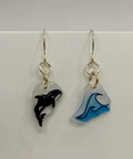 Pair of earrings with whale and wave designs on a white background