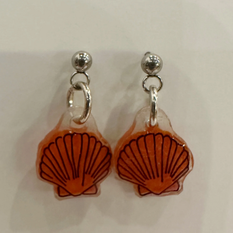 Pair of earrings with orange shell designs on a light background