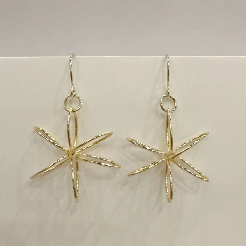 Gold star-shaped earrings on a light gray background