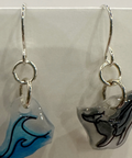 Pair of earrings with whale designs on clear stones against a light background