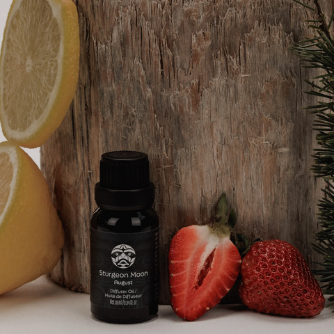Black Sturgeon Moon essential oil bottle with lemons, strawberries, and a wooden block in the background