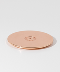 Rose gold circular object on a light gray background