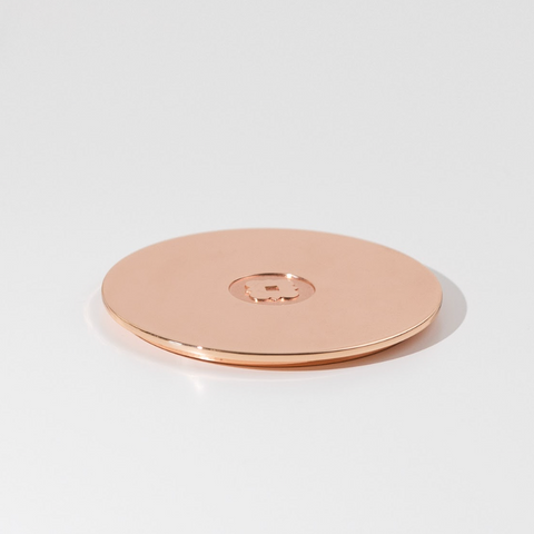 Rose gold circular object on a light gray background