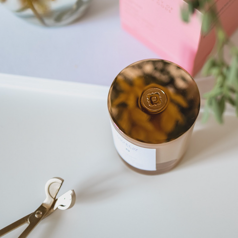 Jar with tortoiseshell lid on a light surface with scissors and plant in the background