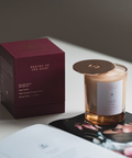 Candle with packaging and card on a light surface