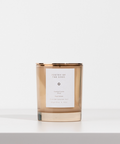 Candle with a gold rim and white label on a light gray background