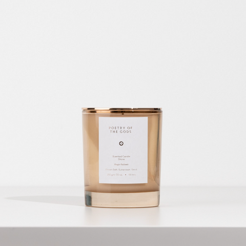Candle with a gold rim and white label on a light gray background