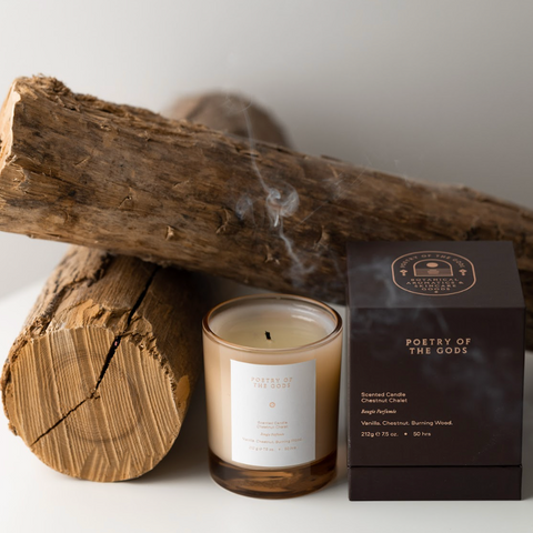 Candle with packaging and wooden logs on a white background