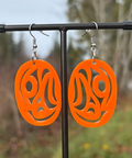 Orange earrings on a stand with a blurred natural background