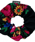 Colorful floral scrunchie on a black background with a brand tag.