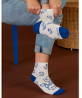 Person wearing white socks with blue accents and cartoon designs, sitting on a chair.