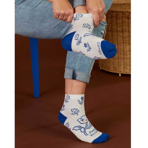 Person wearing white socks with blue accents and cartoon designs, sitting on a chair.