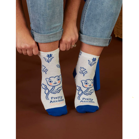 White socks with blue accents and cat designs worn by a person, displayed on a website page.