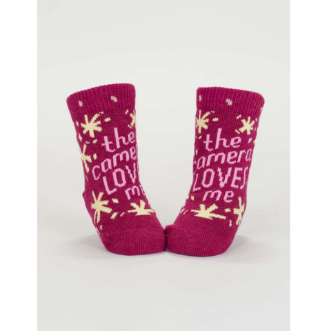 Pair of pink baby socks with text on a white background