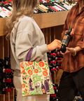 Two women shopping in a store with a product image and price displayed on the screen.