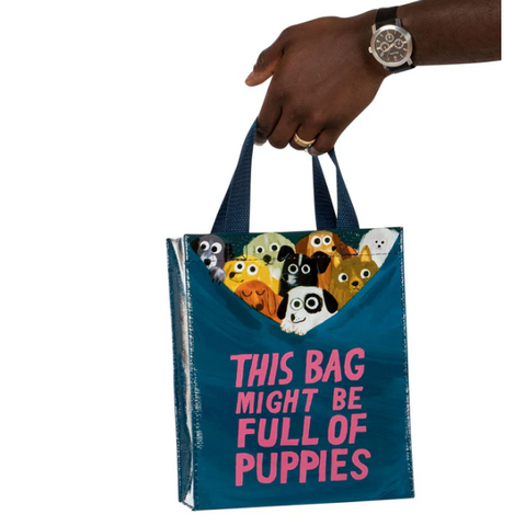 Tote bag with dog illustrations and text held by a hand on a website page.