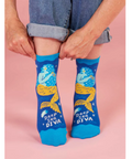 Person wearing blue socks with mermaid design and 'Deep Sea Diva' text on a pink background.
