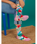 Colorful socks with text and floral design worn by a person sitting on a blue chair.