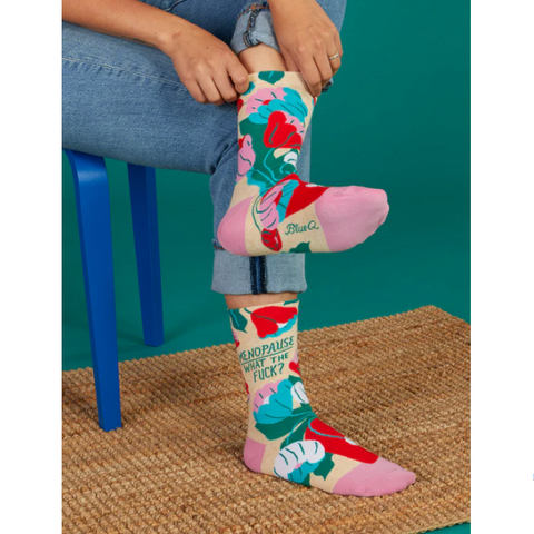 Colorful socks with text and floral design worn by a person sitting on a blue chair.