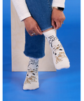 White socks with cat designs worn by a person on a blue background, with product details on the right side.