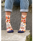 Person wearing colorful socks with text, standing on a stone surface, with product details on the right.
