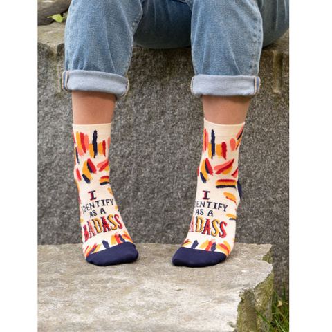 Person wearing colorful socks with text, standing on a stone surface, with product details on the right.