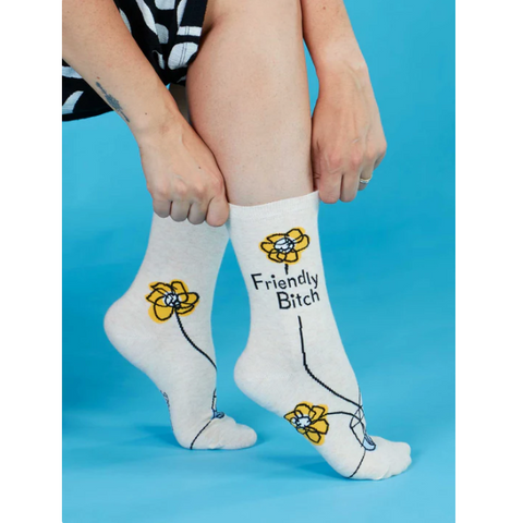 White socks with 'Friendly Bitch' text and floral designs on a blue background
