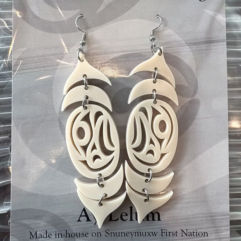 Pair of white earrings with intricate designs on a gray card, displayed on a website page.