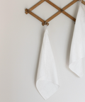 Wooden towel rack with two white towels on a plain wall