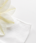 Close-up of a white fabric with a yellow flower petal on a light gray background