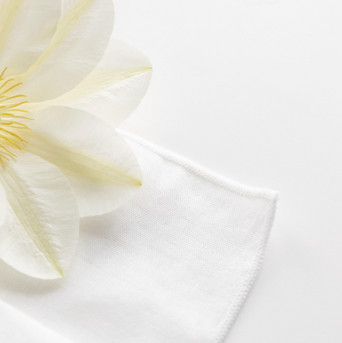 Close-up of a white fabric with a yellow flower petal on a light gray background