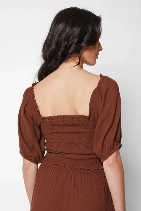 Woman wearing a brown dress with puffed sleeves against a white background