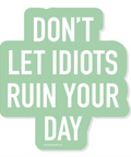 Mint green sign with white text 'DON'T LET IDIOTS RUIN YOUR DAY' on a white background