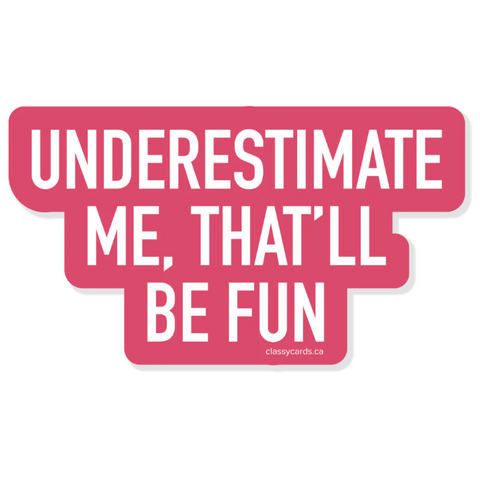 Pink and white sign with text 'UNDERESTIMATE ME, THAT'LL BE FUN' on a white background