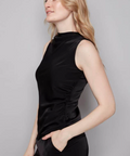 Woman wearing a black sleeveless dress against a gray background
