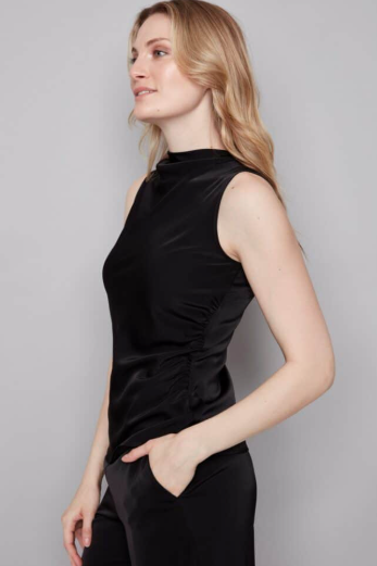 Woman wearing a black sleeveless dress against a gray background