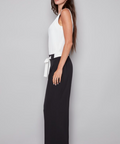 Woman wearing a white top and black wide-leg pants on a gray background
