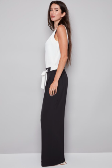Woman wearing a white top and black wide-leg pants on a gray background