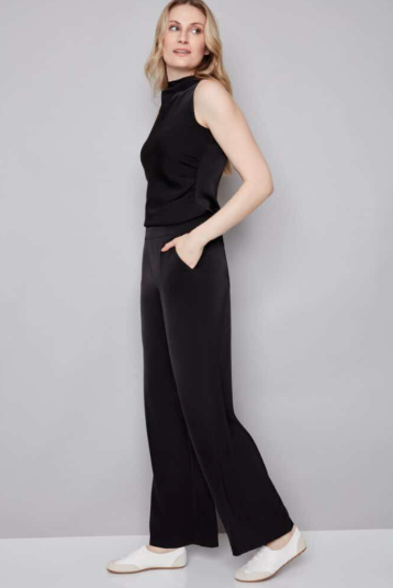 Woman wearing a black sleeveless top and wide-leg pants against a gray background
