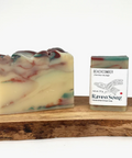 Handmade soap bar with marbled design next to a 'Raven Song' soap packaging on a wooden block.
