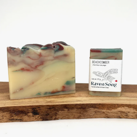 Handmade soap bar with marbled design next to a 'Raven Song' soap packaging on a wooden block.