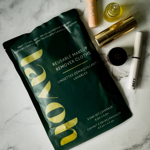 Reusable makeup remover cloths packaging on a marble surface with cosmetic items.