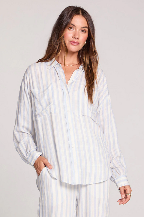 Woman wearing a white striped pajama set against a plain background