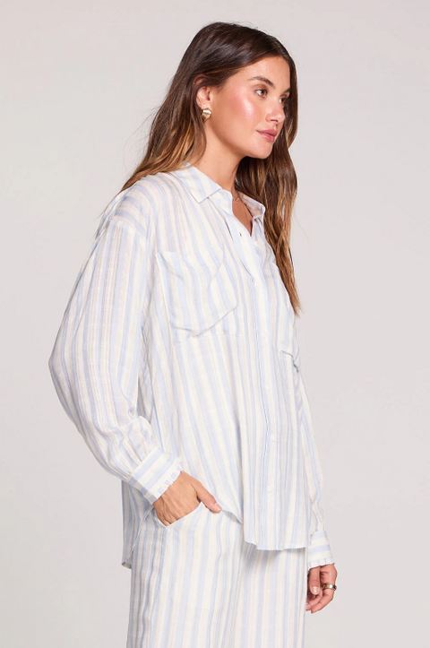 Woman wearing a white and gray striped shirt against a plain background
