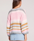 Woman wearing a colorful striped sweater with a plain background