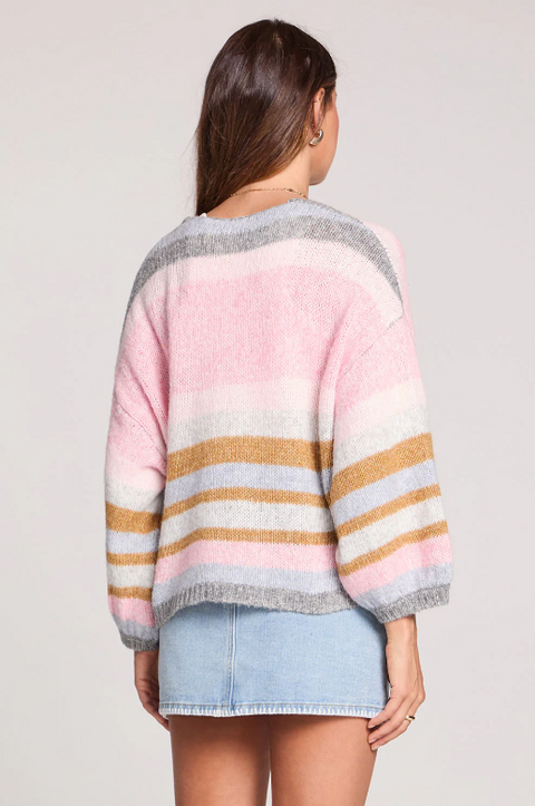 Woman wearing a colorful striped sweater with a plain background