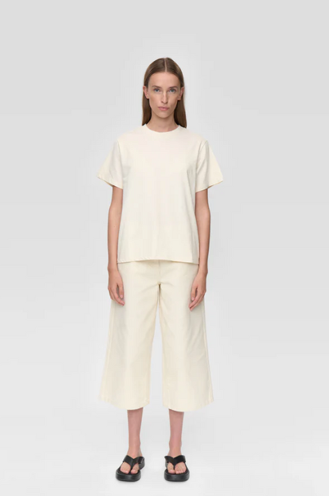 Person wearing a cream-colored outfit on a white background