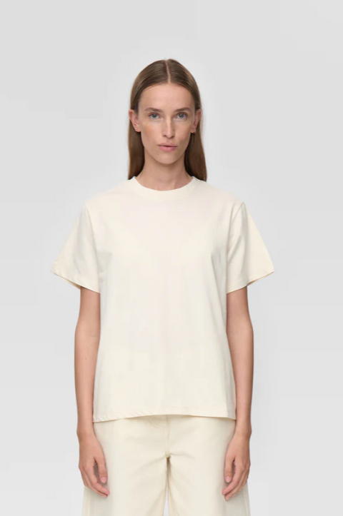 Woman wearing a plain white t-shirt and pants on a light gray background