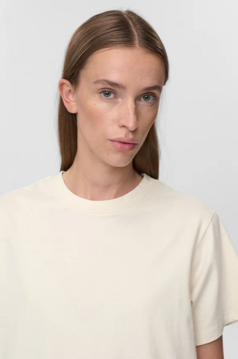 Woman wearing a plain beige t-shirt against a light gray background
